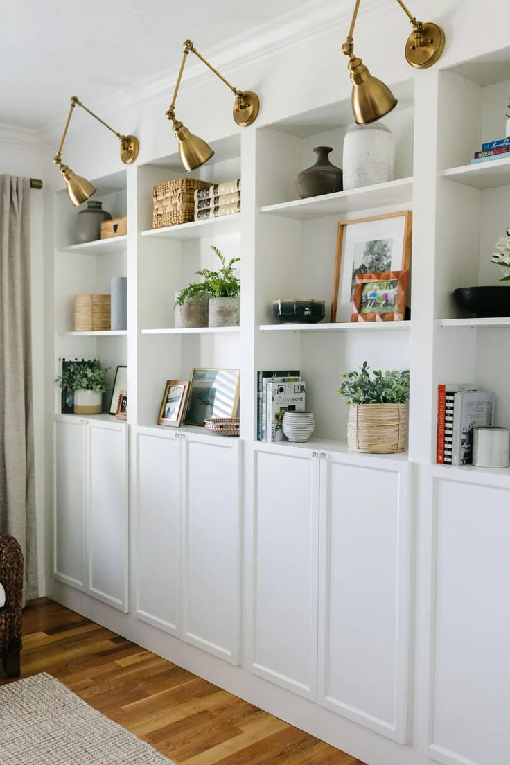 a living room filled with lots of white bookshelves covered in plants and vases