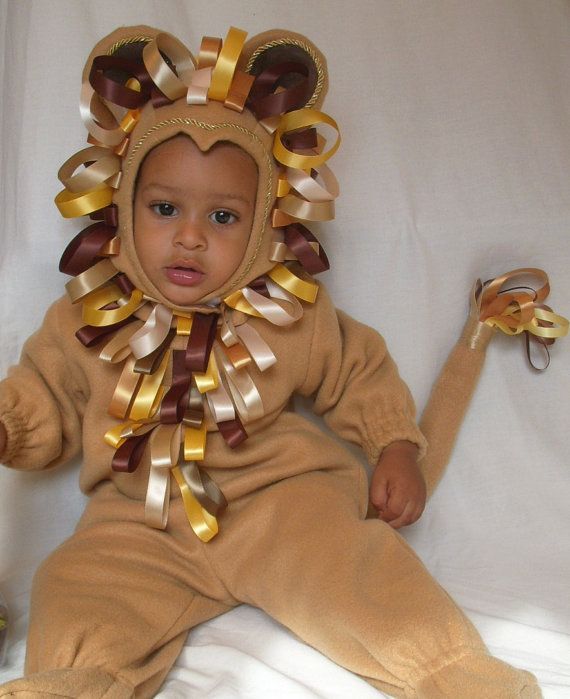 a baby in a lion costume sitting on a bed