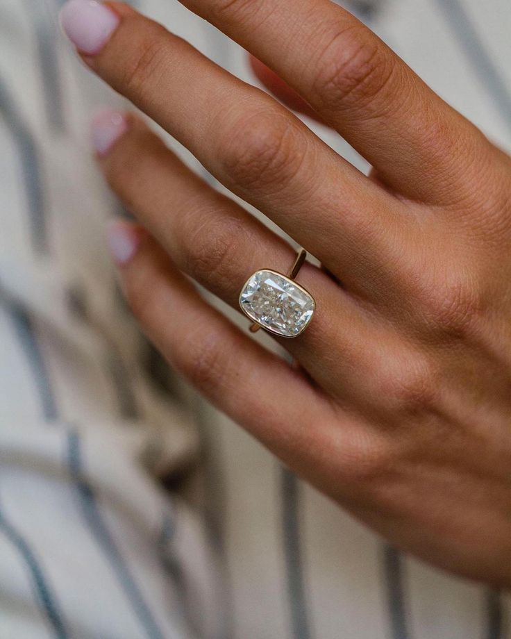 a close up of a person wearing a ring with a large diamond on it's finger