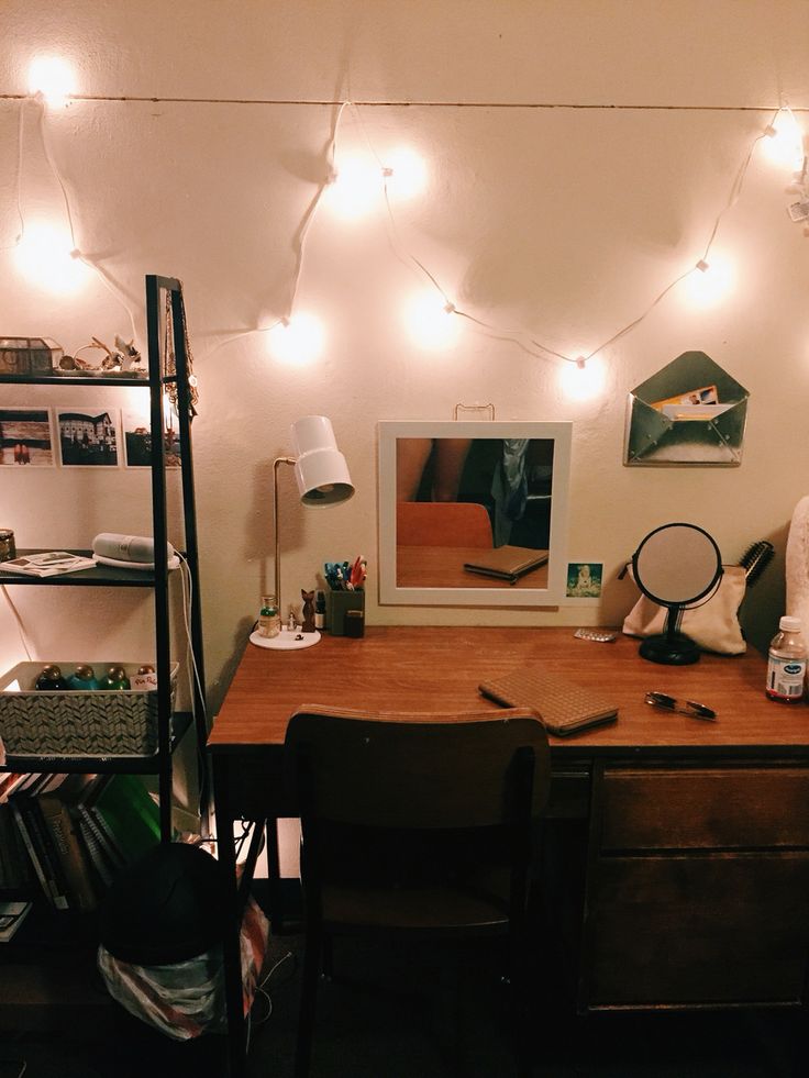 a desk with some lights on the wall above it and a chair in front of it