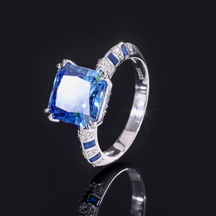 an engagement ring with blue and white stones on the side, set in 18k white gold