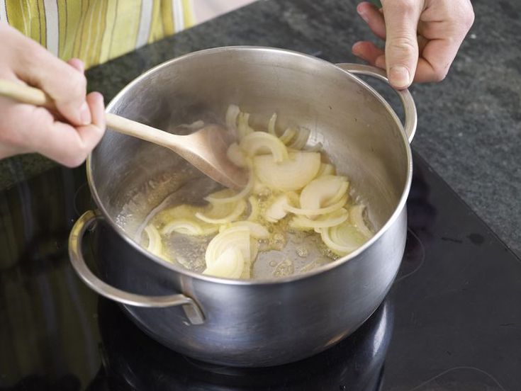 a person stirring food in a pot on the stove