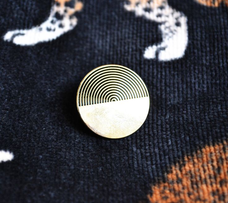 a close up of a metal object on a black and orange blanket with white designs