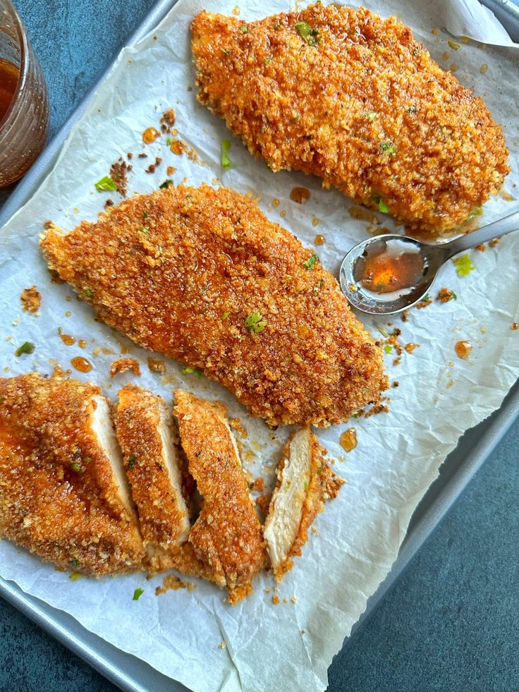 two pieces of fried chicken sitting on top of a pan