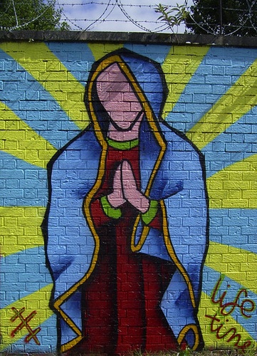 a painted mural on the side of a brick wall depicting a woman holding a child