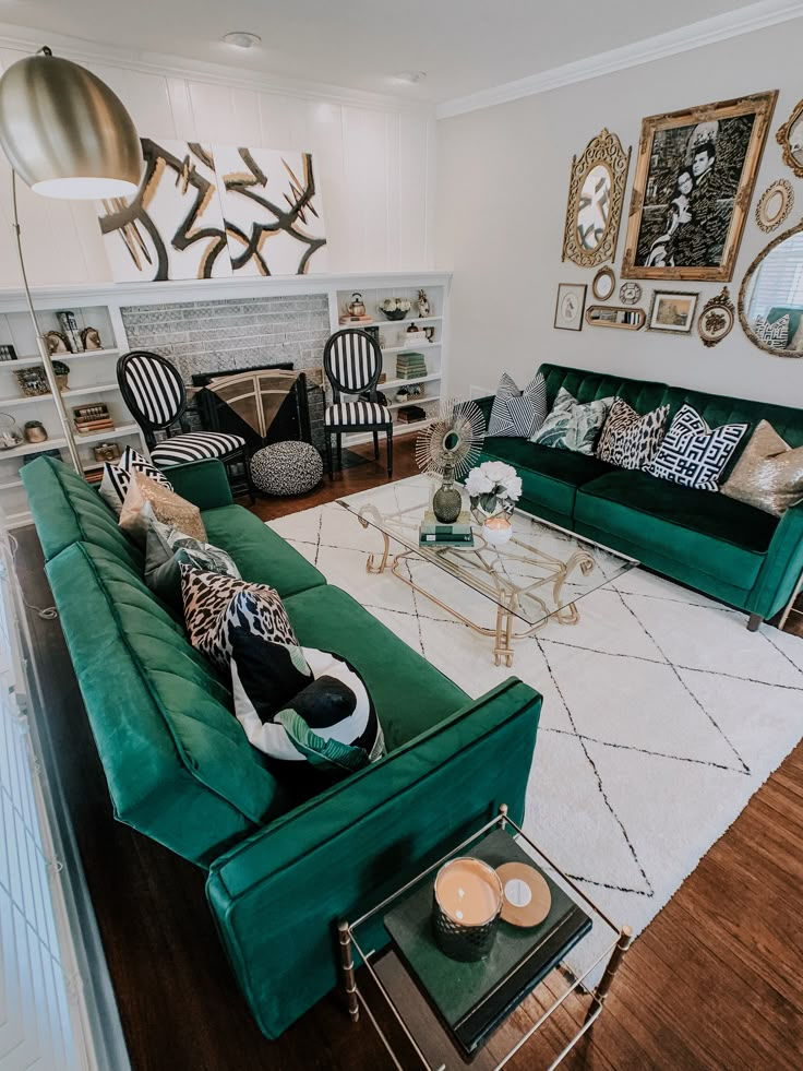 a living room filled with green couches and pillows on top of a white rug