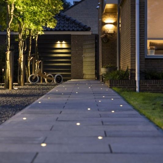 an outdoor walkway with lights on it and bikes parked in the driveway next to it