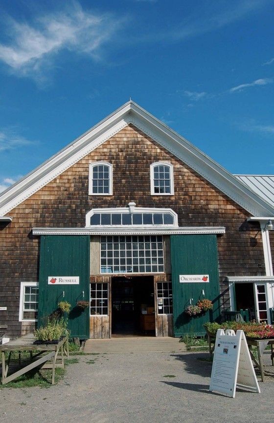 an old building with green shutters and white trim on the front door is shown against a blue sky