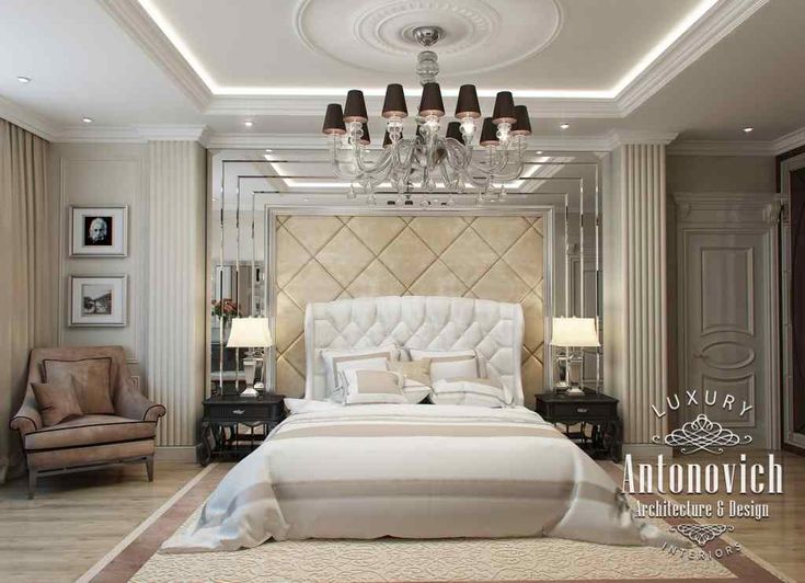 a large bed sitting in the middle of a bedroom next to two chairs and a chandelier