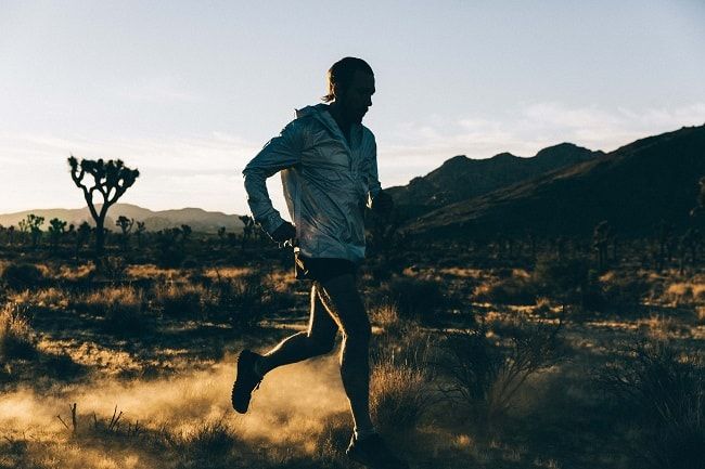 a man running in the desert at sunset