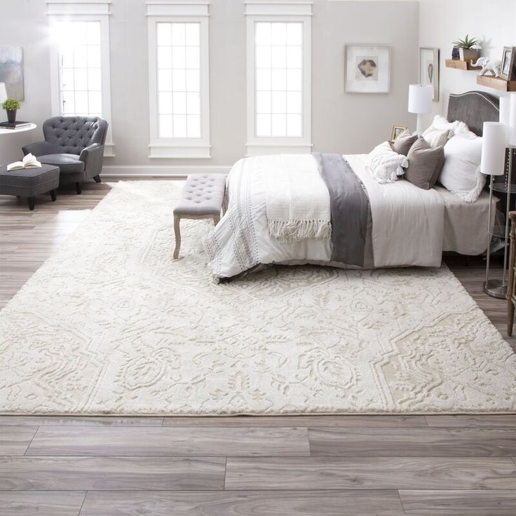 a large white rug in a bedroom with a bed and two chairs next to it