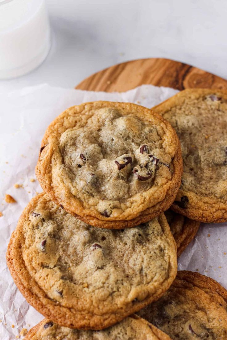 chocolate chip cookies are stacked on top of each other next to a glass of milk