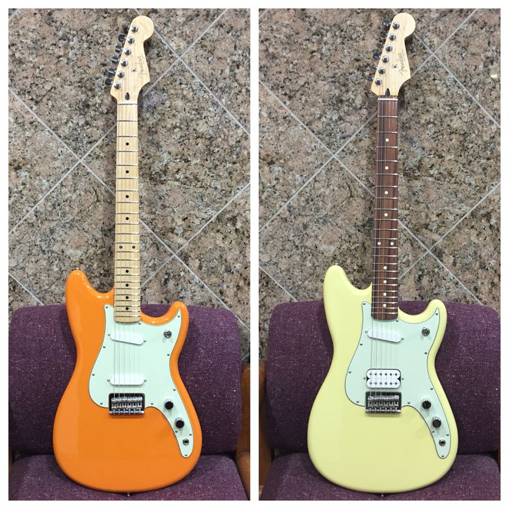 two guitars sitting side by side on a couch