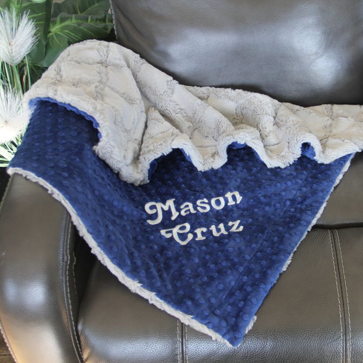 a blue and white blanket sitting on top of a leather chair next to a plant