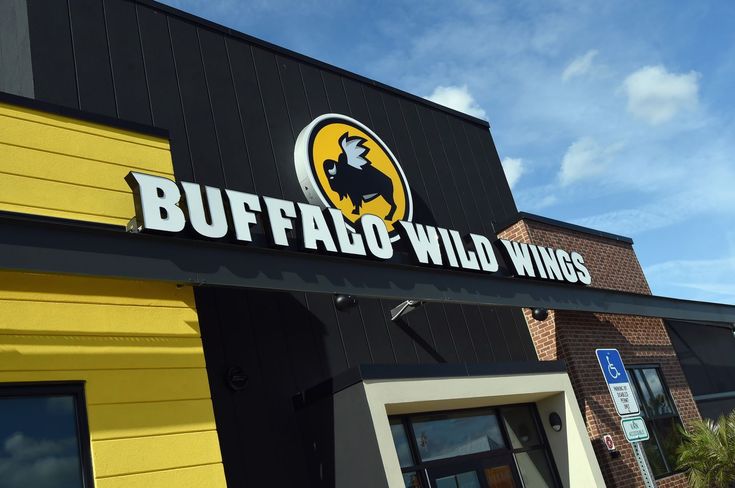 the sign for buffalo wild wings is hanging from the side of a building that has yellow and black siding