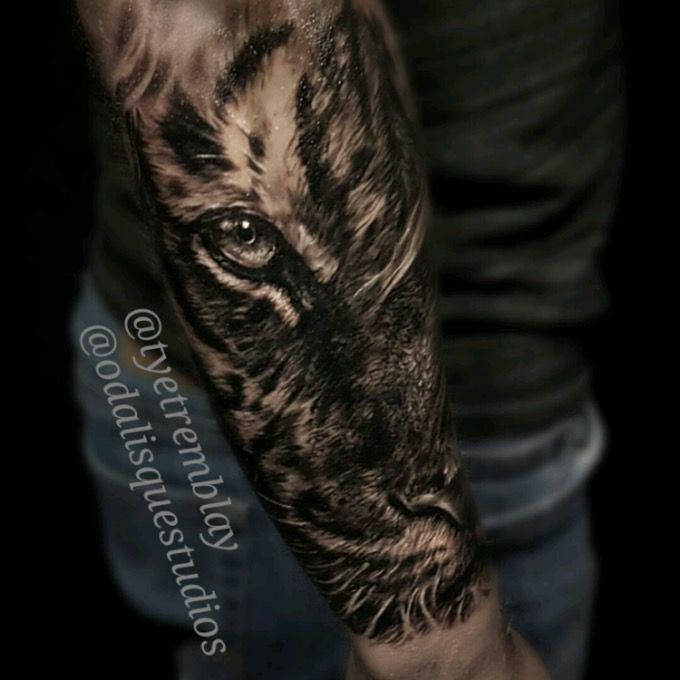 a man's arm with a black and white tiger tattoo on the left forearm