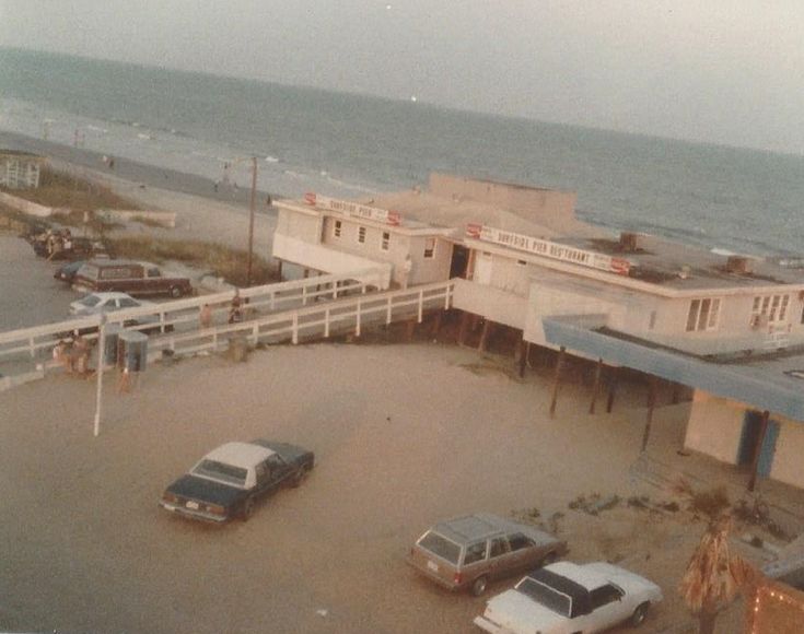 there are cars parked in the parking lot next to the beach and boardwalks that lead into the ocean