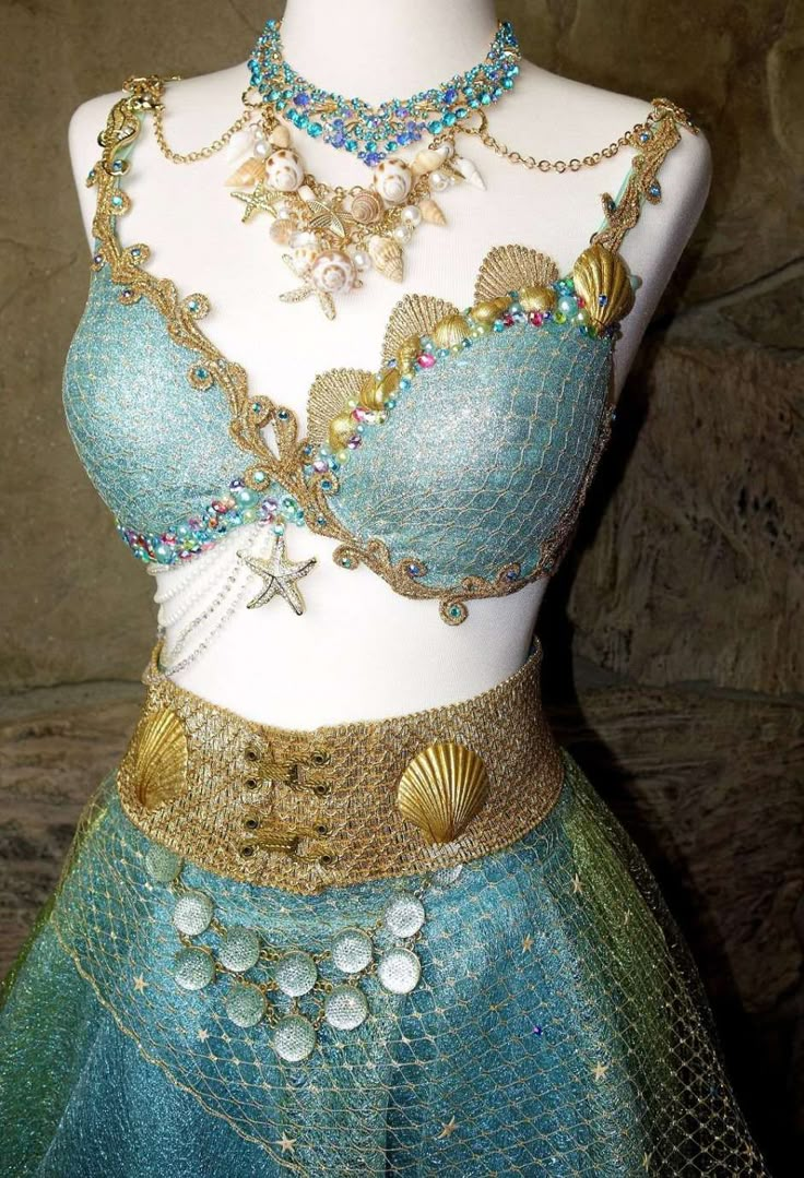 a mannequin wearing a blue and green dress with gold jewelry on it's chest