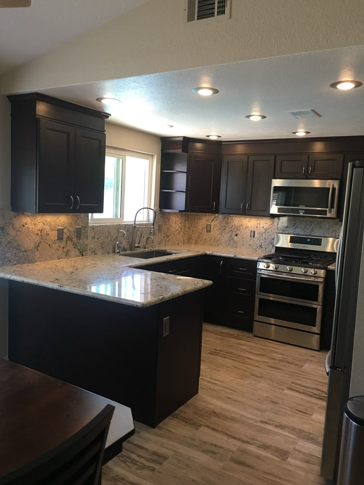 a kitchen with black cabinets and stainless steel appliances