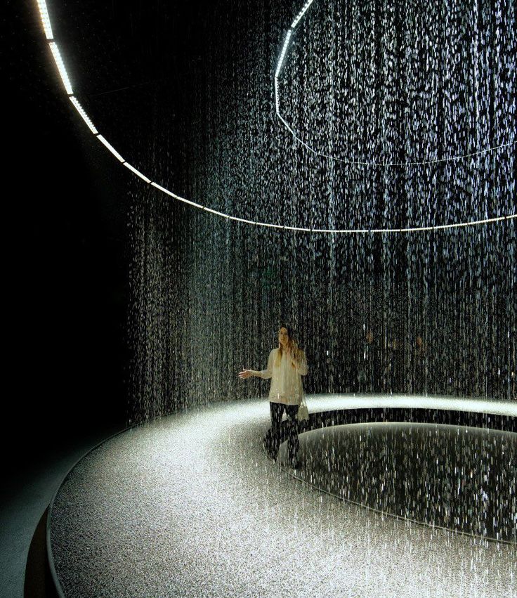 a woman sitting on a bench in front of a rain shower at the end of a tunnel