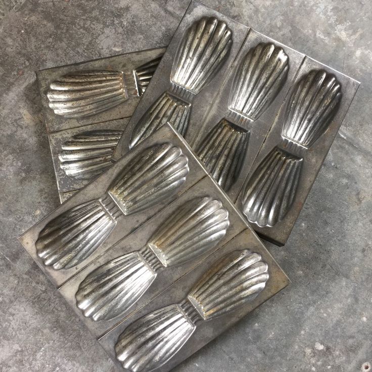 six metal utensils sitting on top of a cement floor next to each other