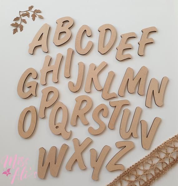 wooden letters and numbers are laid out on a white surface with lace trimming around them