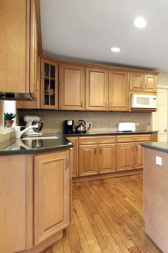 an empty kitchen with wooden cabinets and black counter tops is seen in this image from the front view