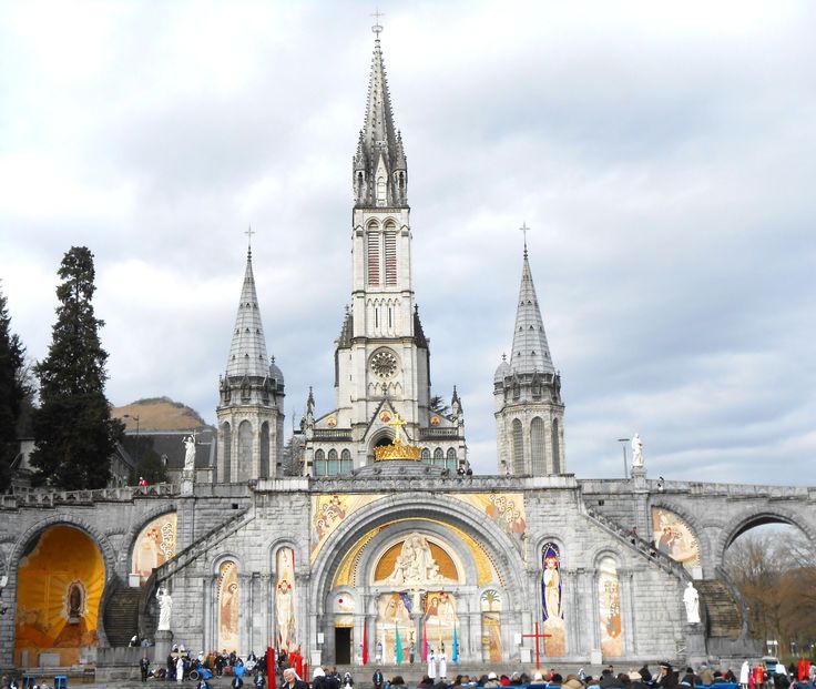 people are standing in front of an old building with many spires and arches on it