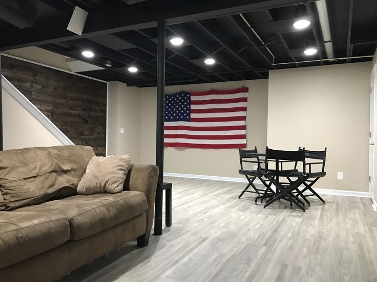 a living room filled with furniture and an american flag hanging on the wall above it