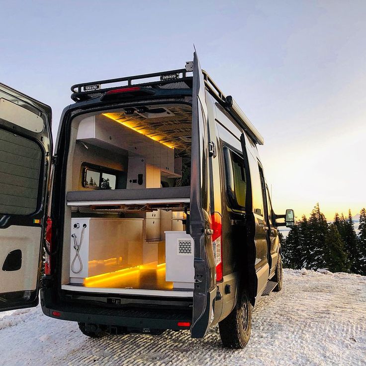 the back end of a van with its doors open on top of snow covered ground