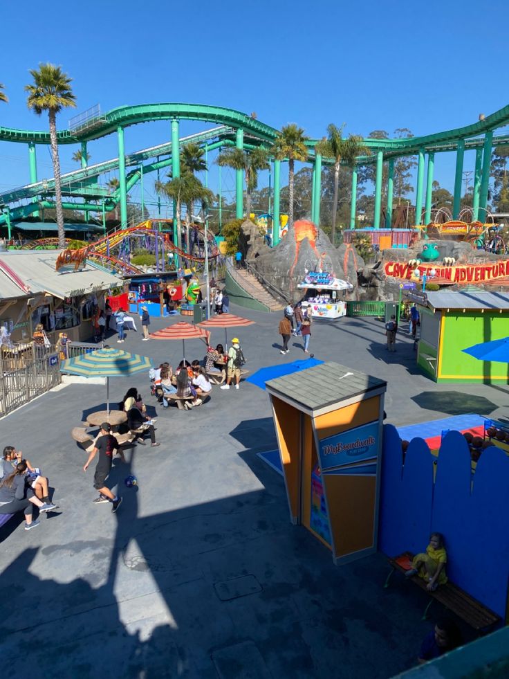 an amusement park with people sitting and walking around