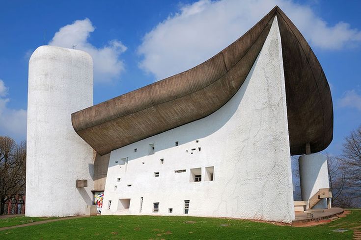 a large white building sitting on top of a lush green field under a blue sky