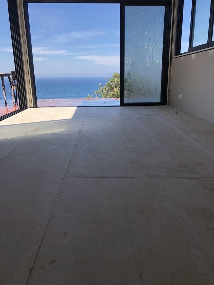 an empty room with large windows overlooking the ocean