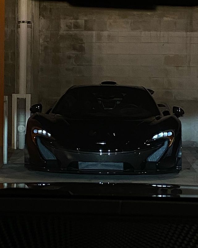 a black sports car is parked in a garage with its hood up and lights on