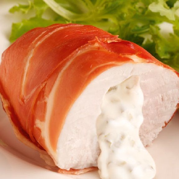 a white plate topped with meat covered in sauce and lettuce next to a salad