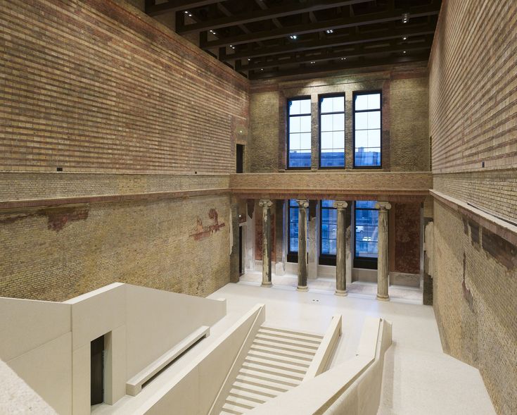 the interior of a building with exposed brick walls and columns, windows, and stairs