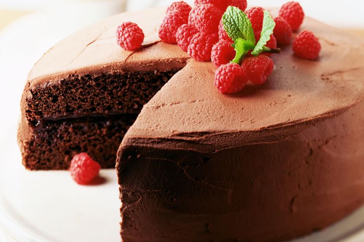 a piece of chocolate cake with raspberries on top and one slice cut out