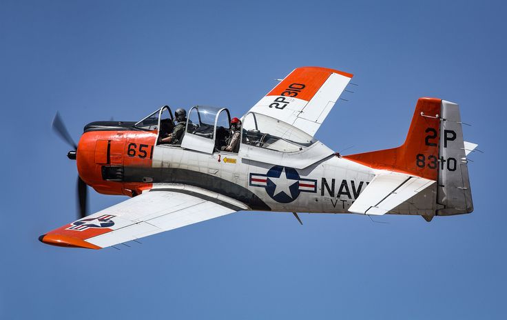 an orange and white airplane flying in the sky with propellers on it's wings