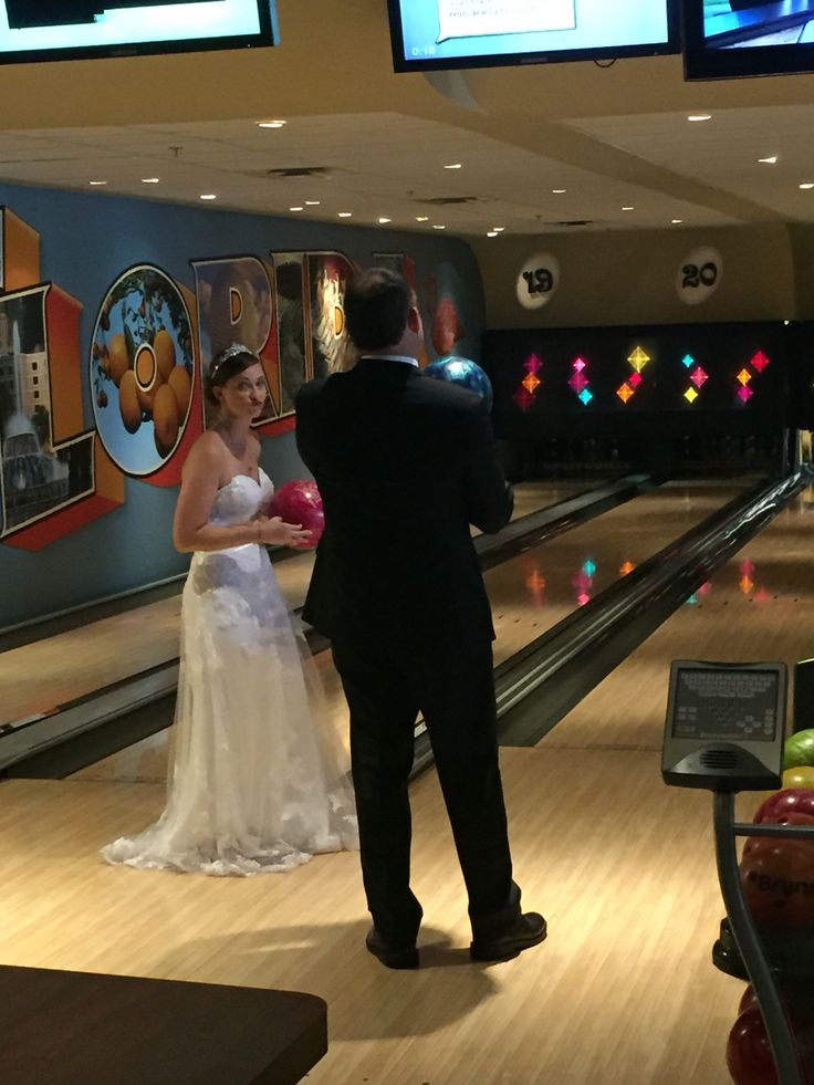 a bride and groom standing at the end of a bowling alley