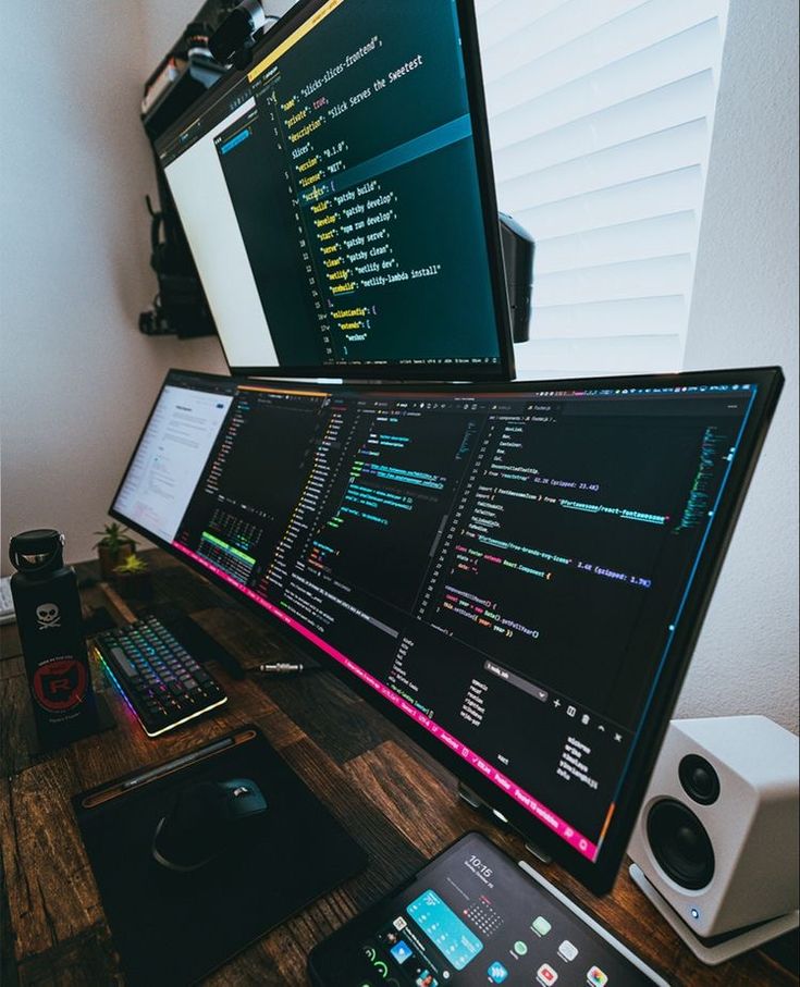 two computer monitors sitting next to each other on a wooden desk in front of a laptop