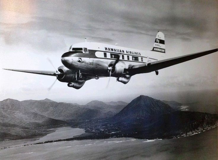 an airplane is flying over the water and mountains in black and white, with one landing gear down