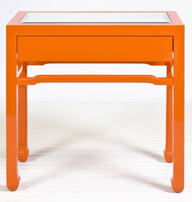 an orange end table with a glass top and bottom shelf on one side, against a white background