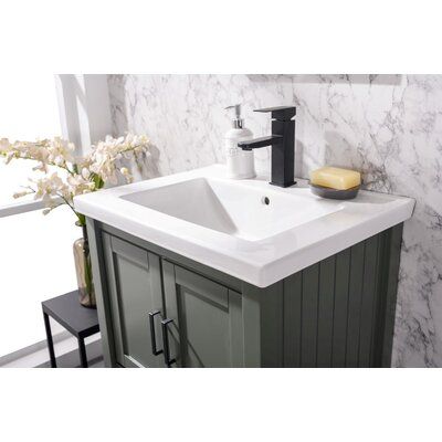 a bathroom sink sitting under a window next to a counter top with a soap dispenser