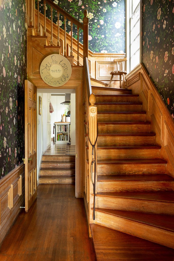 the stairs are made of wood and have floral wallpaper on them, as well as a clock