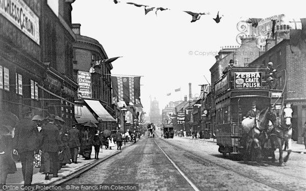 an old black and white photo of people walking down the street