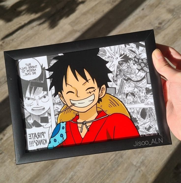 a hand holding up a framed cartoon with an image of gohan on the front