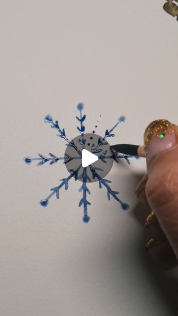 someone is drawing a snowflake on the wall with blue paint and glitters