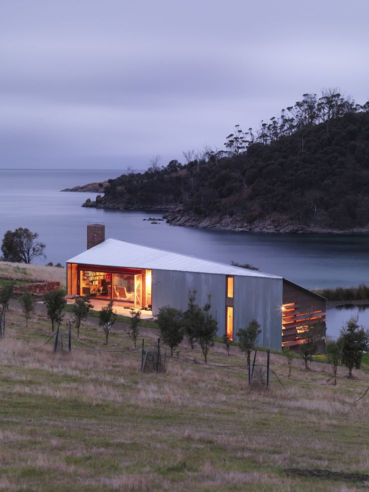 a house on the side of a hill with water in the background