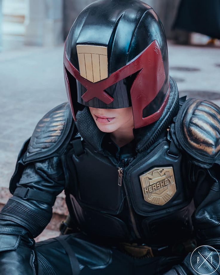 a man dressed in black and red sitting on the ground