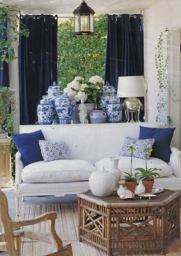 a living room filled with white furniture and blue and white vases on the windowsill